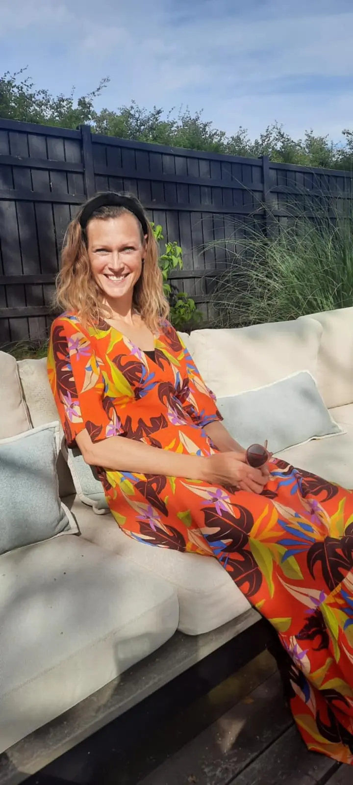 Smilende kvinde i farverig kjole på terrasse